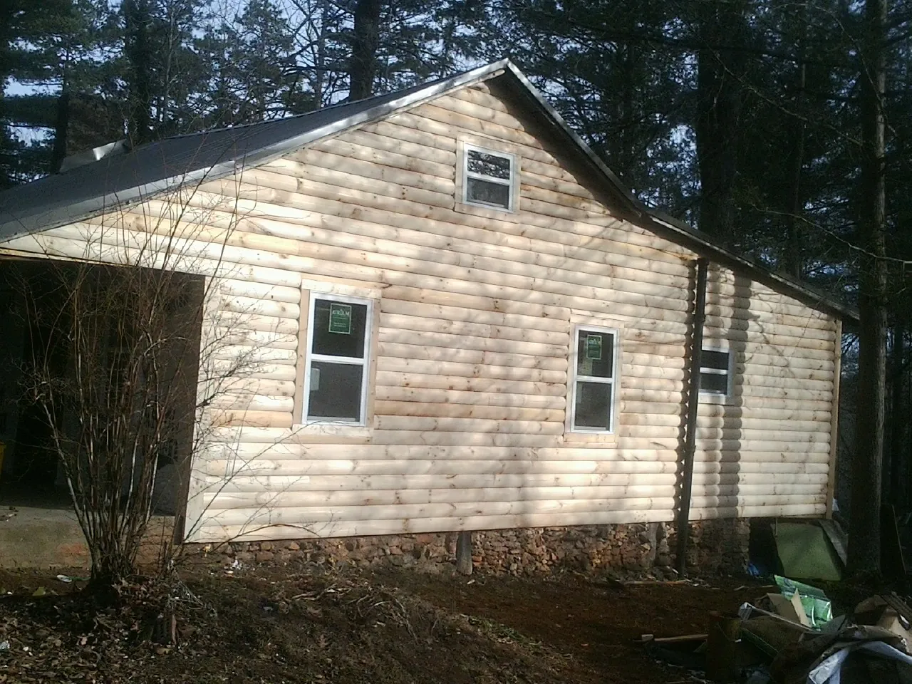 New log siding and dark metal roofing on a gable end in Vidor