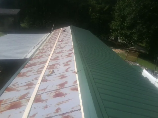 Old rusted panels beside newly installed green metal roofing — Wind Damage Roof Repair by Roofing Brothers in Vidor