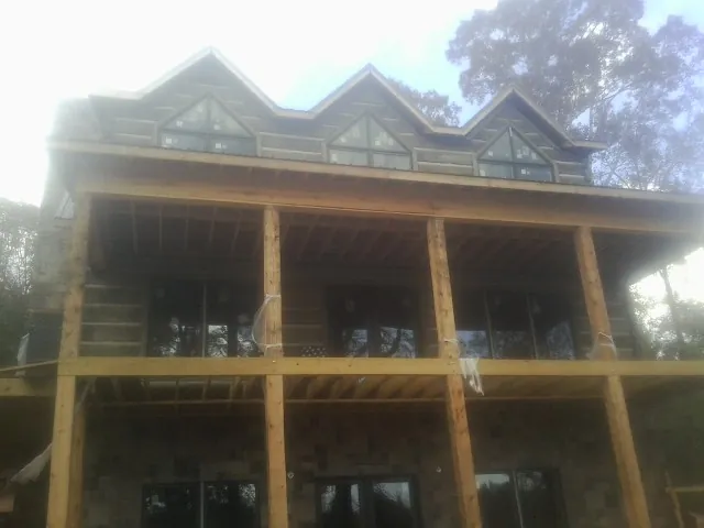 Dormers and porch framing on a large log home under construction — Roof Coating work by our crew in Vidor