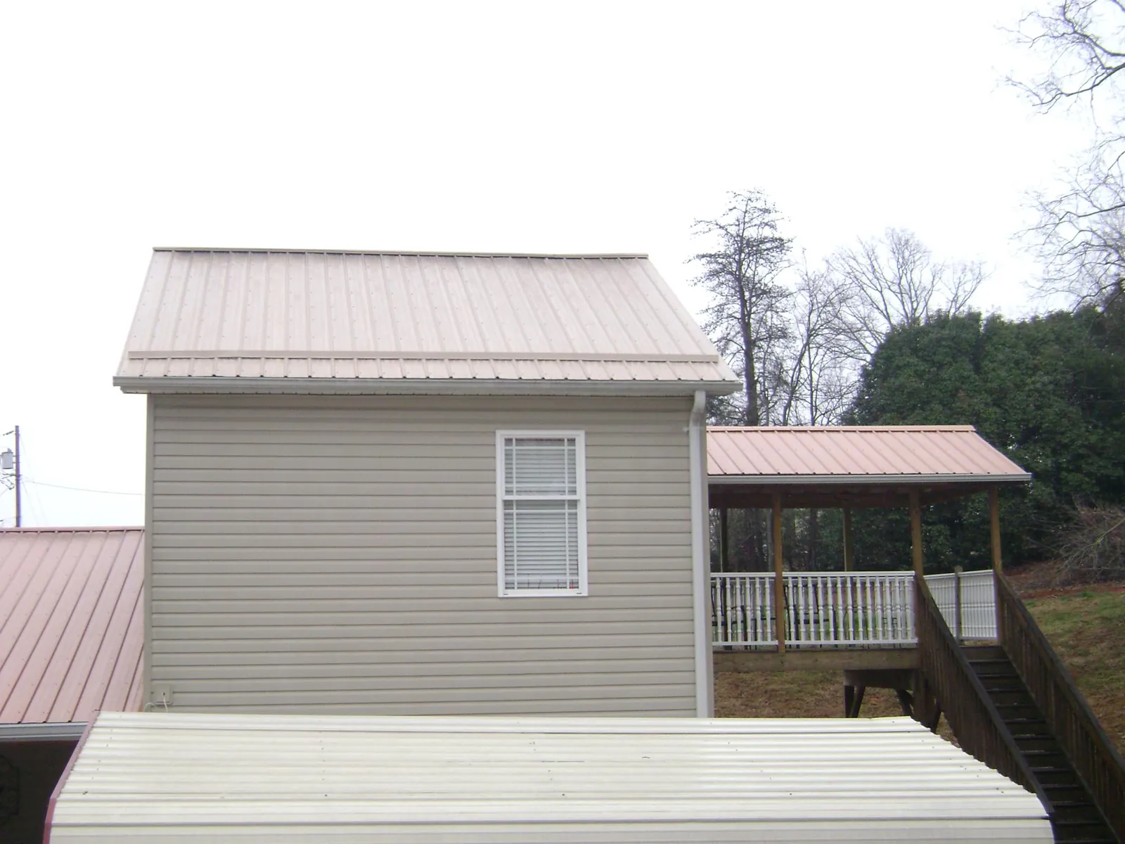 Tan metal roofs on a two story addition and attached porch, from a Roof Replacement job in Vidor