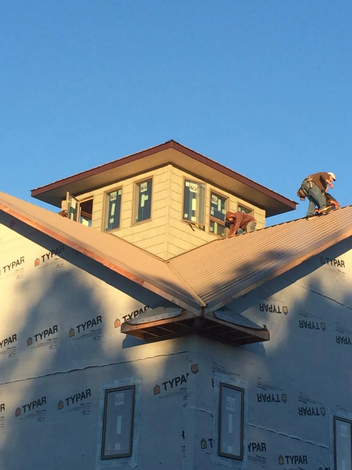 Roofers working around a rooftop cupola on a new metal roof at sunset — Roof Waterproofing in Vidor by Roofing Brothers
